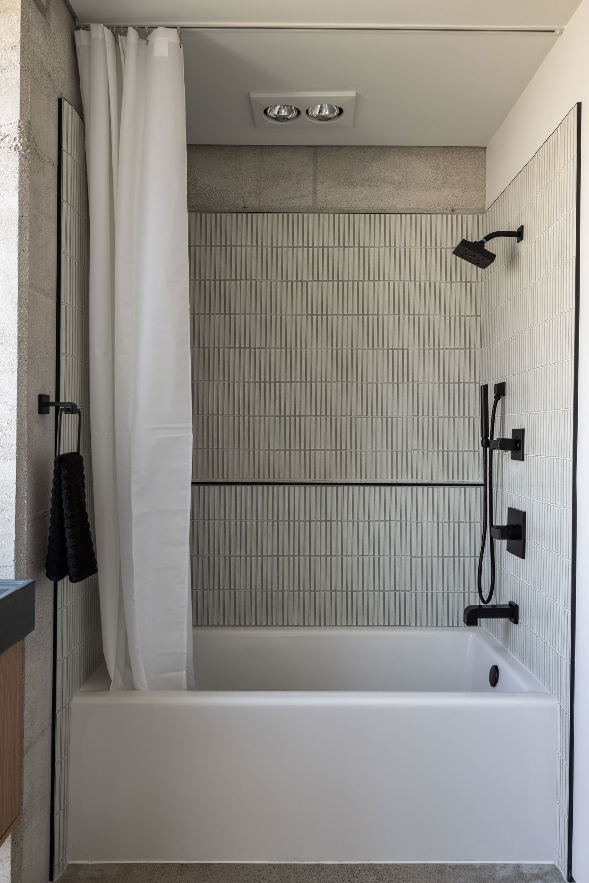Japanese tile, matte black plumbing fixtures, and rammed earth converge in unity in this modern bathroom