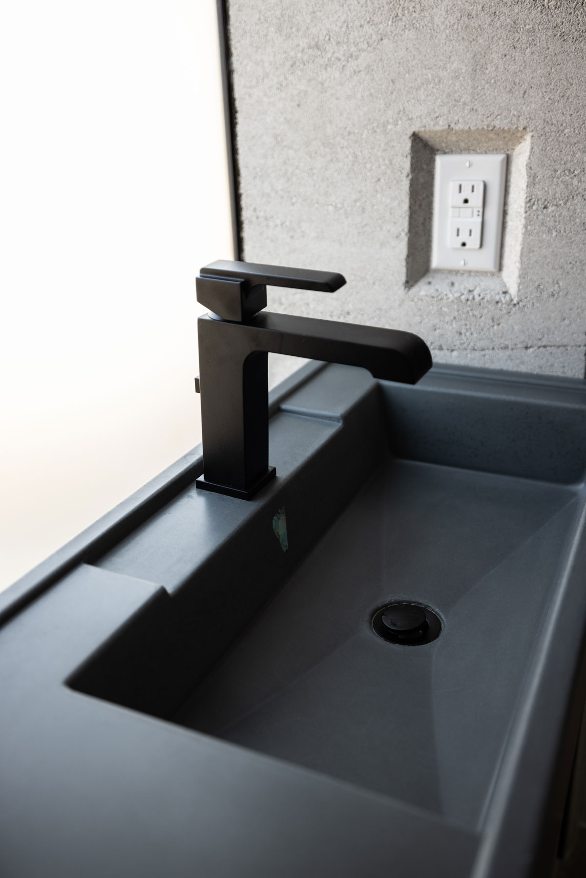A custom concrete sink, made of GFRC, installed in a modern rammed earth house