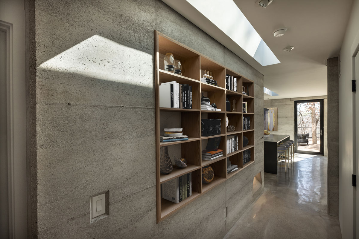 The entry of the CALX Cabin features a built in oak bookcase recessed into the rammed earth wall.