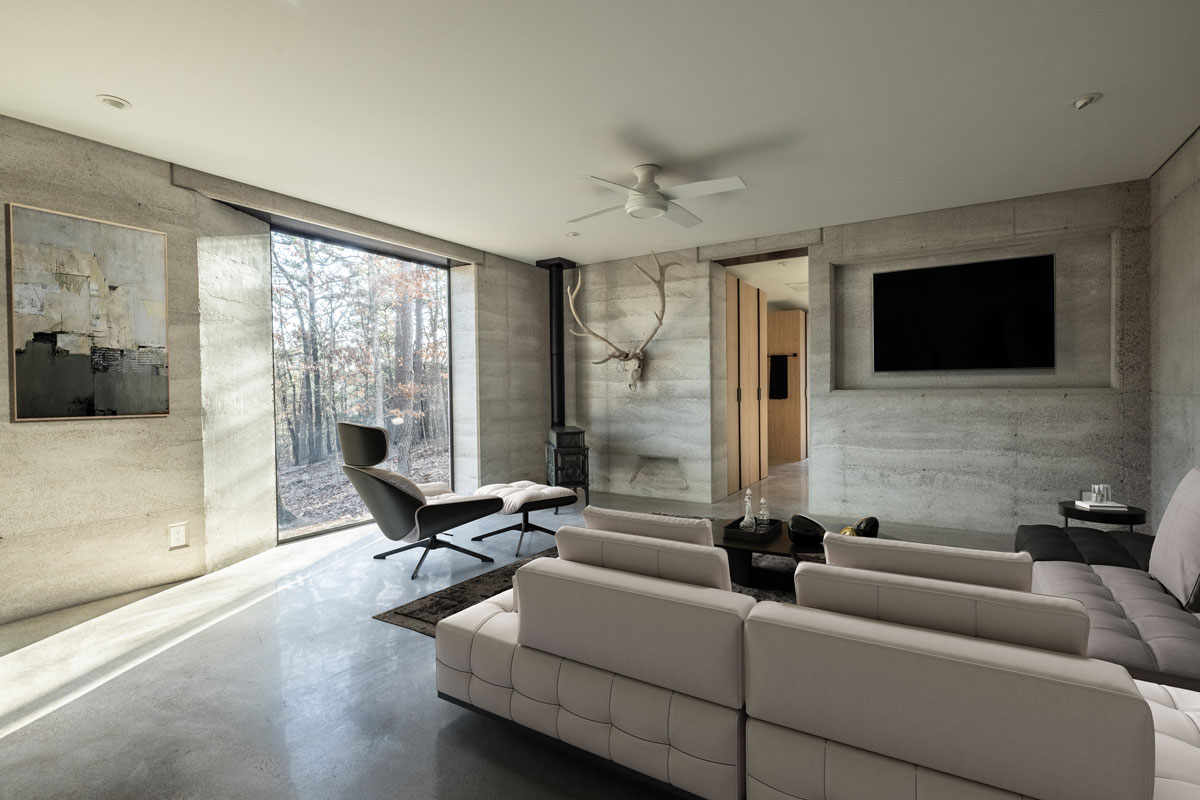 This modern living room could be on the cover of Dwell Magazine with the rammed earth walls, polished concrete floors, and massive steel and glass windows.