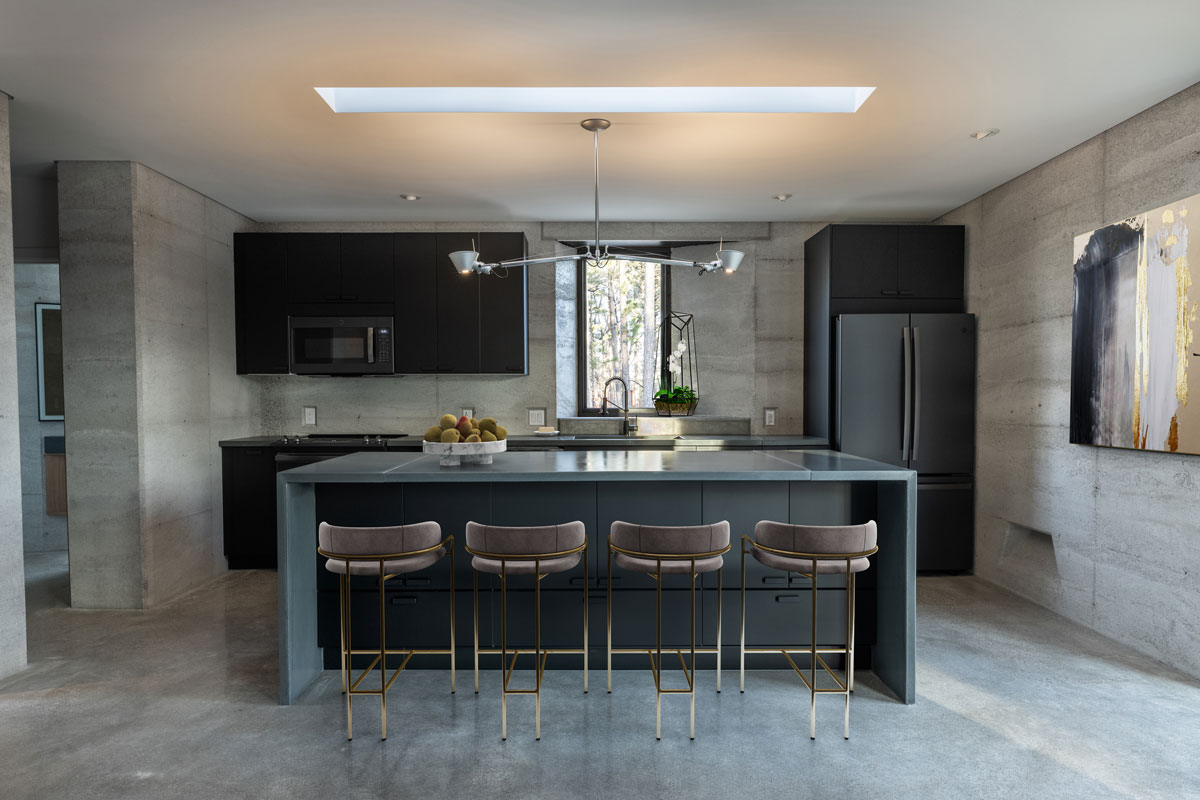 The minimal kitchen in the rammed earth house is warm with the organic textures and thoughtful space design.