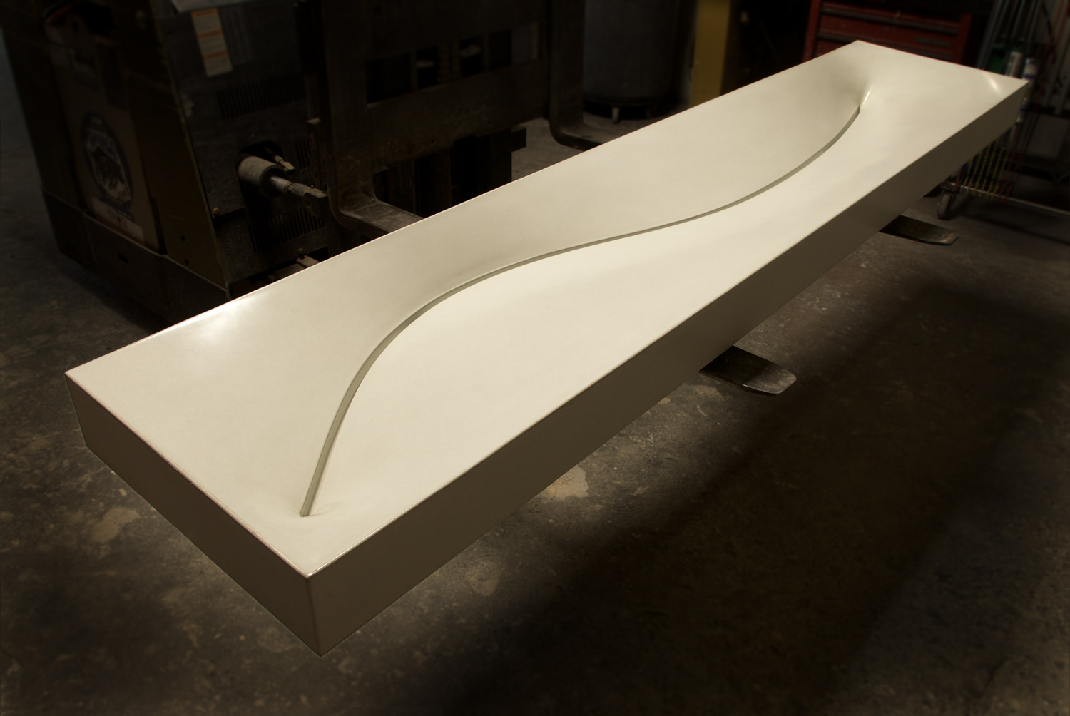A curved, organic modern concrete trough sink with a curved slot drain. 