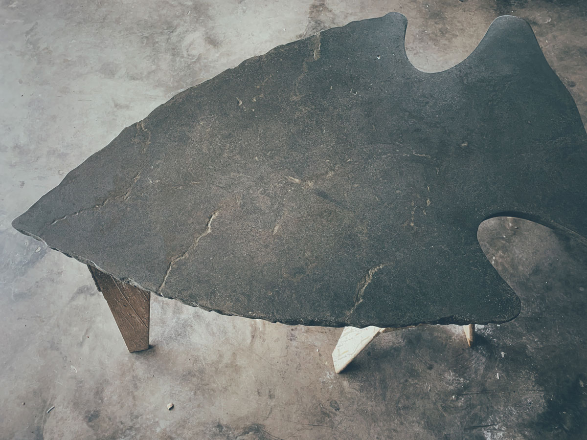 A concrete coffee table shaped like an arrowhead for a rustic lodge