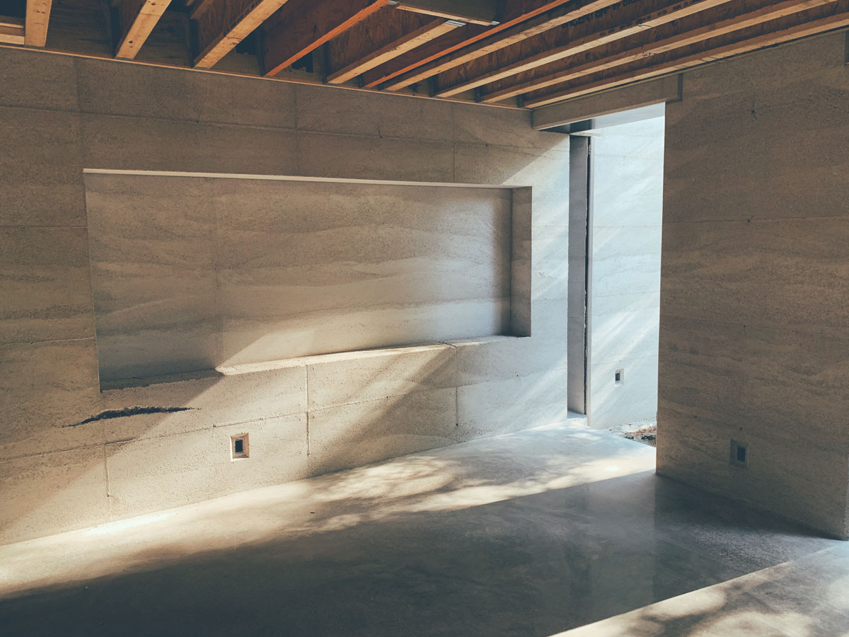 Late afternoon sun reflecting off the polished concrete terrazzo floor on the rammed earth wall