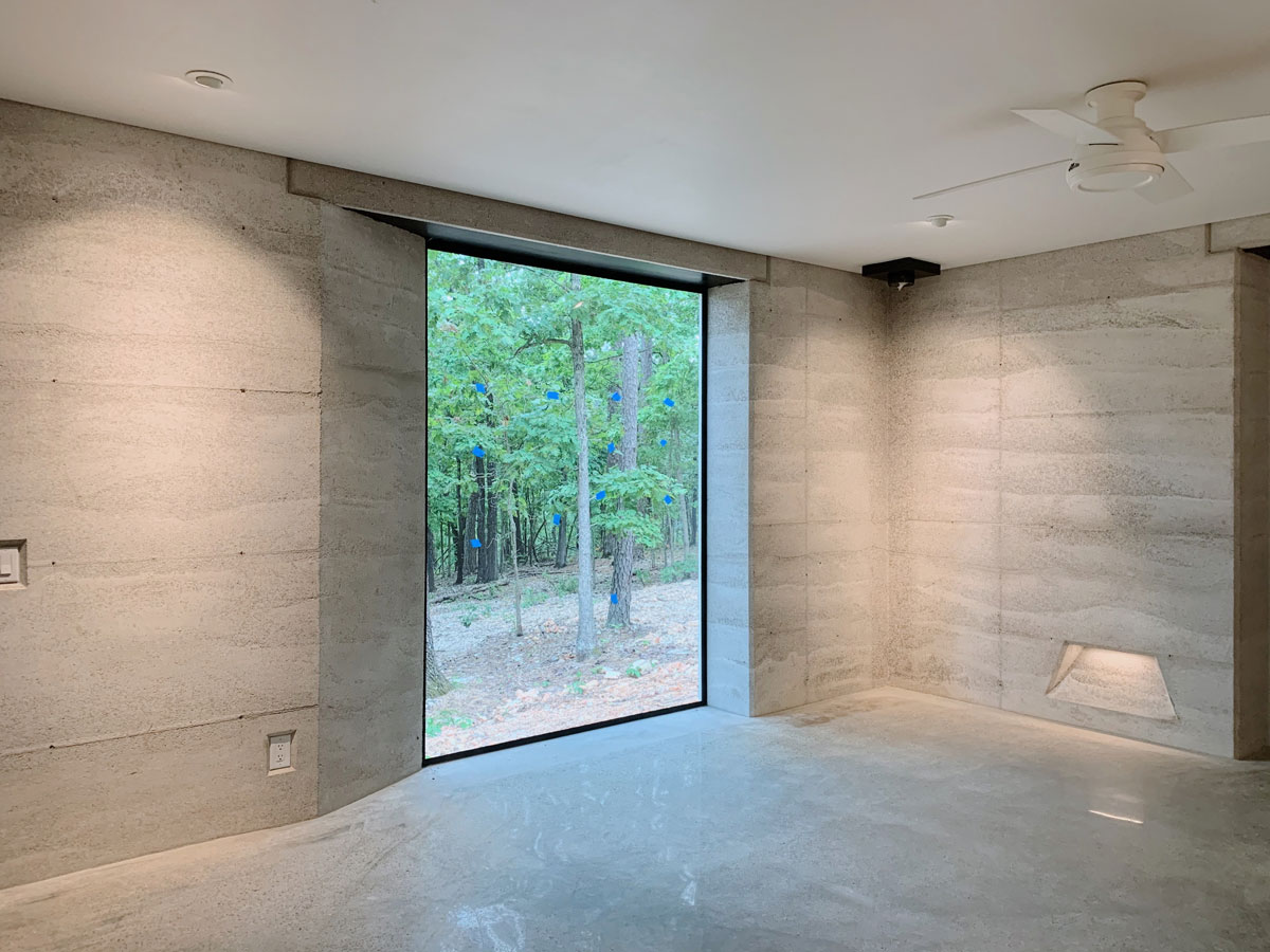 A view from inside the rammed earth cabin looking out into the woods