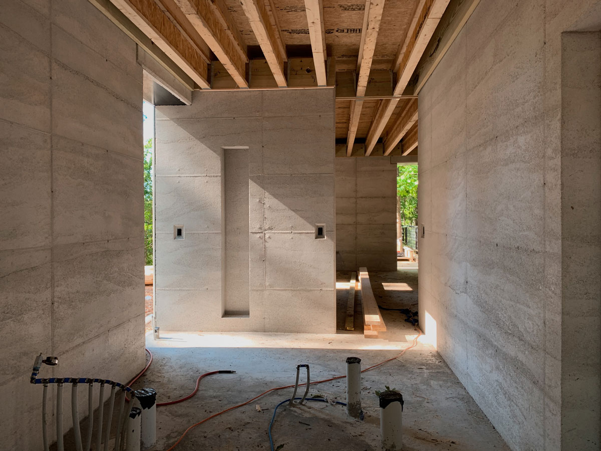 morning light streaming into the rammed earth cabin. The luminance of the limestone rammed earth walls is quite striking.